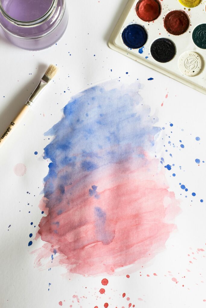 pexels photo 587958 587958 Vibrant watercolor painting with blue and red gradient, brush, and palette.